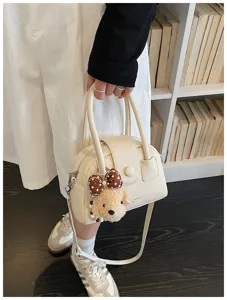 Chic women's cream bowling handbag with cute plush dog pendant, versatile crossbody bag.