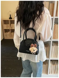 Detail view of black bowling handbag with cute bear plush pendant and chic retro design.