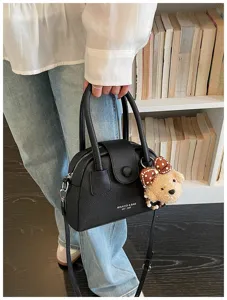Black leather bowling bag detail showing exquisite texture, handles and cute bear pendant.