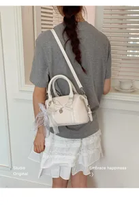 Detailed shot of a chic white top-handle shoulder bag with bow and lace charm for women daily.