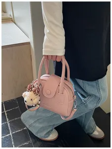 Detailed view of a cute pink bowling handbag with a fluffy bear charm, casual styling design.