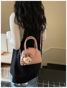 Detailed view of women pink bowling bag shoulder strap cute bear charm indoor setting
