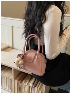 Stylish pink bowling handbag for women with cute bear pendant, versatile crossbody bag.