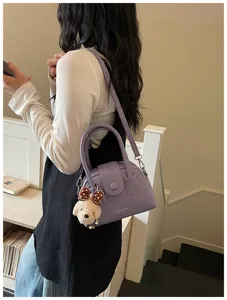Detail view of trendy purple bowling handbag for women featuring cute puppy charm pendant.