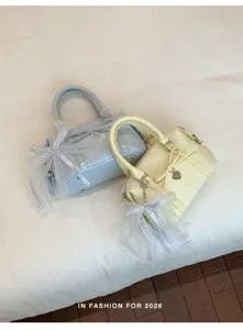 Detailed view of sweet style patent leather bow handbag, exquisite heart charm and delicate lace.
