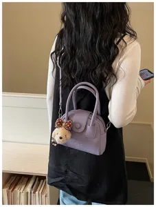 Chic purple bowling bag featuring a cute plush puppy charm and practical crossbody strap.
