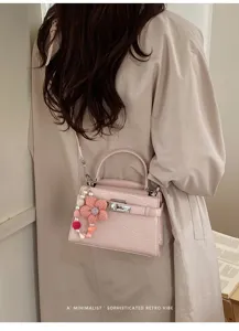 Chic pink croc-embossed Kelly bag with floral charm, stylish retro shoulder crossbody bag.
