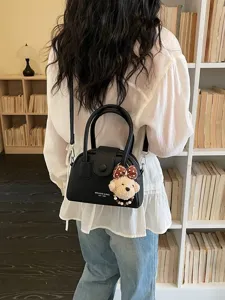 Stylish black bowling handbag for women, versatile crossbody pillow bag with cute bear pendant.