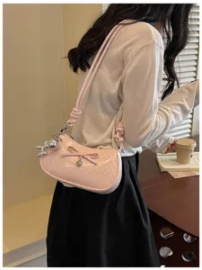 Detailed closeup view of the stylish pink polka dot shoulder bag with cute bow and metal charms.