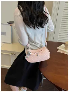 Detailed shot of a pink polka dot shoulder bag featuring a cute bow and metallic charm.