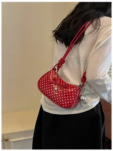 Red polka dot shoulder bag detail view showcasing cute bow and metal rabbit charm accessory.
