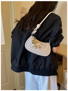 Chic white polka dot shoulder bag for women, stylish crossbody handbag with cute bow and silver pendant.