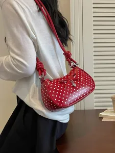 Red polka dot shoulder bag for women, stylish crossbody handbag with bow and heart pendant.