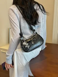 Chic black polka dot shoulder bag for women, stylish underarm handbag with bow and charm.