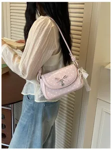 Chic pink polka dot shoulder bag for women, featuring a cute bow and heart charm detail.