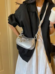 Trendy silver polka dot shoulder bag for women, stylish baguette handbag with charms.
