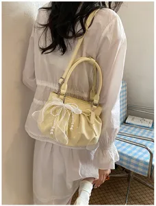 Detail view of a soft leather pleated cloud handbag with polka dots, bow, and pearl detail.