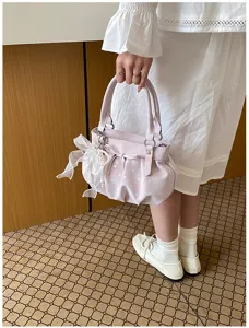 Detail view of a cute pink polka dot handbag with bow and pearl, soft leather cloud bag.