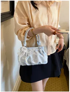 Detailed view of light blue polka dot handbag featuring cute organza bow and pearl charms.