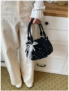 Chic black polka dot handbag with delicate ruffles, elegant pearl pendant, and soft leather.
