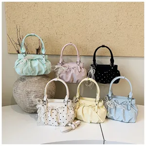Detail of ruched polka dot handbags in multiple colors with pearl bow charms and soft leather.