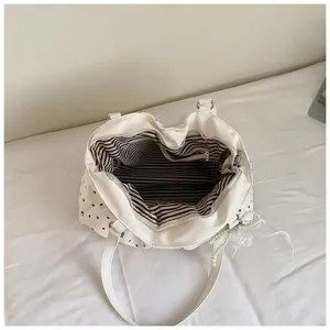 Detailed top view showing interior striped lining and pearl pendant of the pleated polka dot bag.
