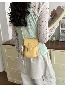 Detailed view of a stylish yellow crossbody mini phone bag with chic charm decoration.