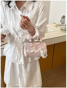 Detailed view of pink polka dot barrel bag with lace trim, cute bow and fluffy puppy charm.