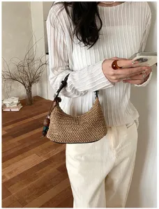Primo piano dettagliato di una borsa estiva in paglia da donna con ciondoli di perline.