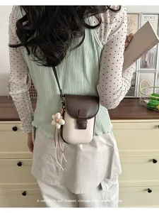 Detail shot of a vintage style mini crossbody phone bag with floral charm and contrast flap.