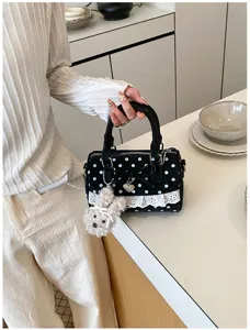Black polka dot handbag detail with lace trim, bow, and fluffy plush charm for summer style.