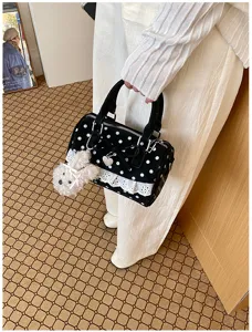 Detail shot of sweet black polka dot pillow handbag with white lace trim and cute puppy charm.