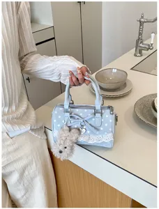Close-up of light blue polka dot handbag detail featuring sweet lace trim and fluffy dog charm.