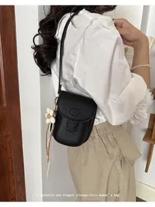 Black leather mini crossbody bag for women, stylish phone shoulder bag with cute flower charm.