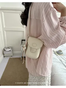 Minimalist vintage mini cross-body phone bag with elegant flap design and cute charm detail.