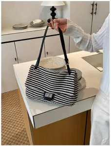 Vista detallada de un elegante bolso de hombro de paja a rayas en una cocina moderna.
