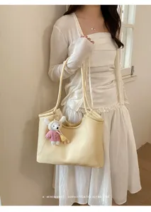 Detail view of minimalist beige leather tote bag with cute rabbit pendant for women.