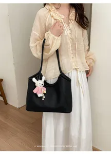 Black leather slouchy tote bag detail with cute knitted rabbit charm and minimalist retro vibe.