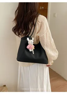 Detail view of the black leather shoulder bag with a cute crochet rabbit keychain charm.