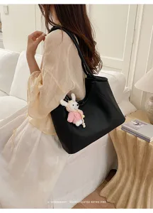 Detail view of the elegant black PU leather tote bag featuring a cute knitted rabbit charm.