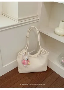 Detailed view of cream white leather shoulder tote bag with cute crochet rabbit keychain.