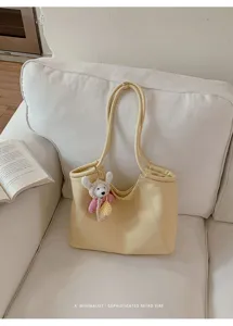 Minimalist light yellow leather tote bag with cute knit plush keychain detail for women.