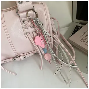Pink leather Boston handbag with stylish keychain, zipper closure, and chic lacing details.