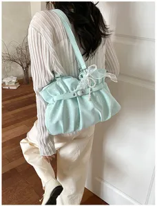 Detail view of a light blue polka dot ruffled shoulder bag with cute pearl and bow charms.