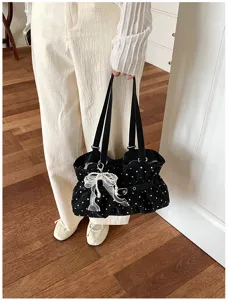 Detail shot of the black polka dot ruffed shoulder bag showcasing the elegant pearl bow pendant.