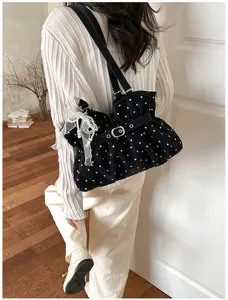 Detail view of a stylish black polka dot ruched shoulder bag with pearl ribbon pendant.