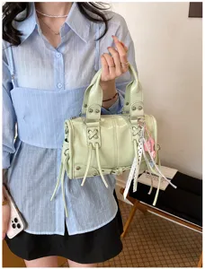 Green patent leather Boston handbag with metal rivets and stylish charms for daily commute.