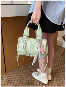 Light green Boston handbag for women, stylish crossbody bag with tassels and metallic hardware.