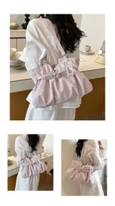 Detail shot of a chic pink polka dot gathered shoulder bag with pearl and lace decor, stylish.