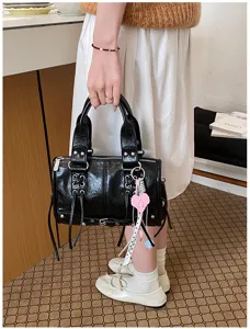 Black patent leather Boston handbag with metal hardware, chic commuting shoulder bag.